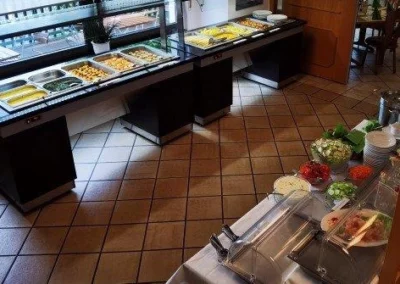 Buffet mit verschiedenen Gerichten in einem Restaurant, darunter Salate und warme Speisen.