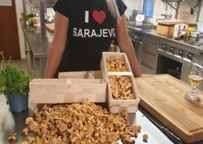 Frau in einer Küche mit frischen Pilzen und einem Glas Bier auf einem Tisch.